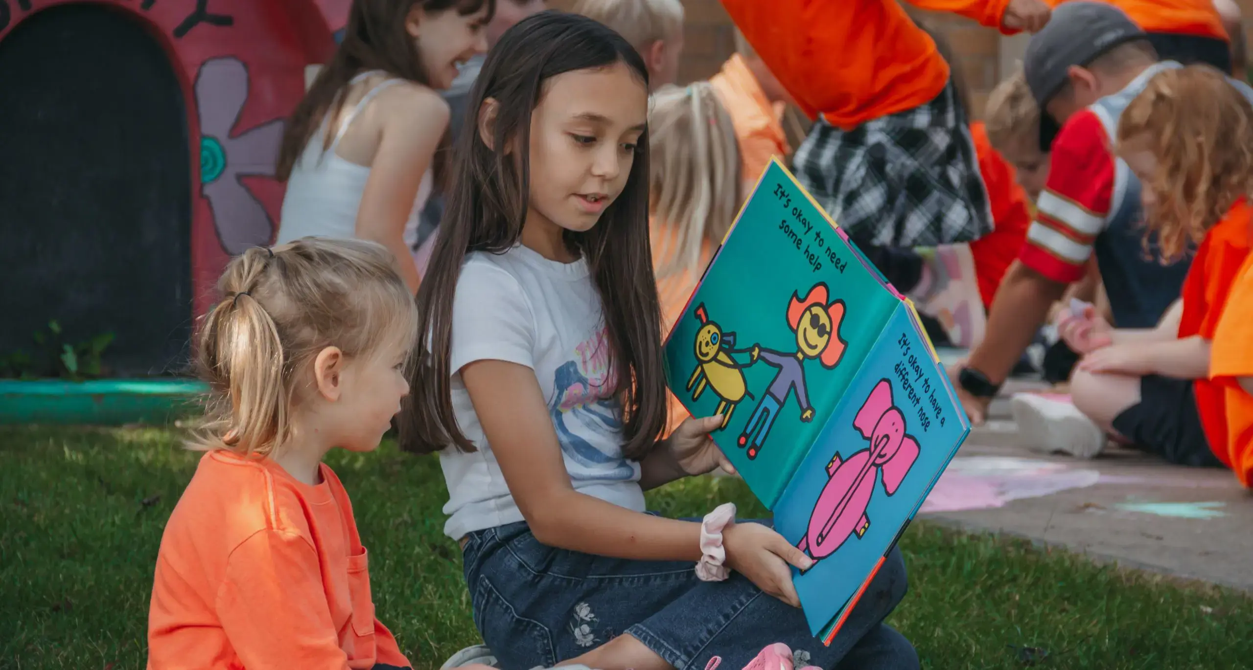 Middle school student reading a book to a lower school student