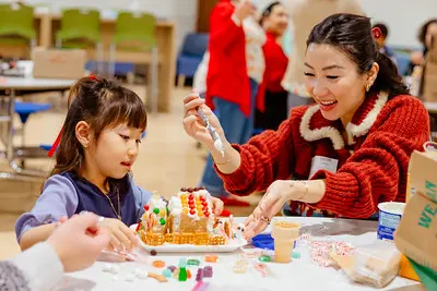 Lower school student and parent decorating gingerbread house together
