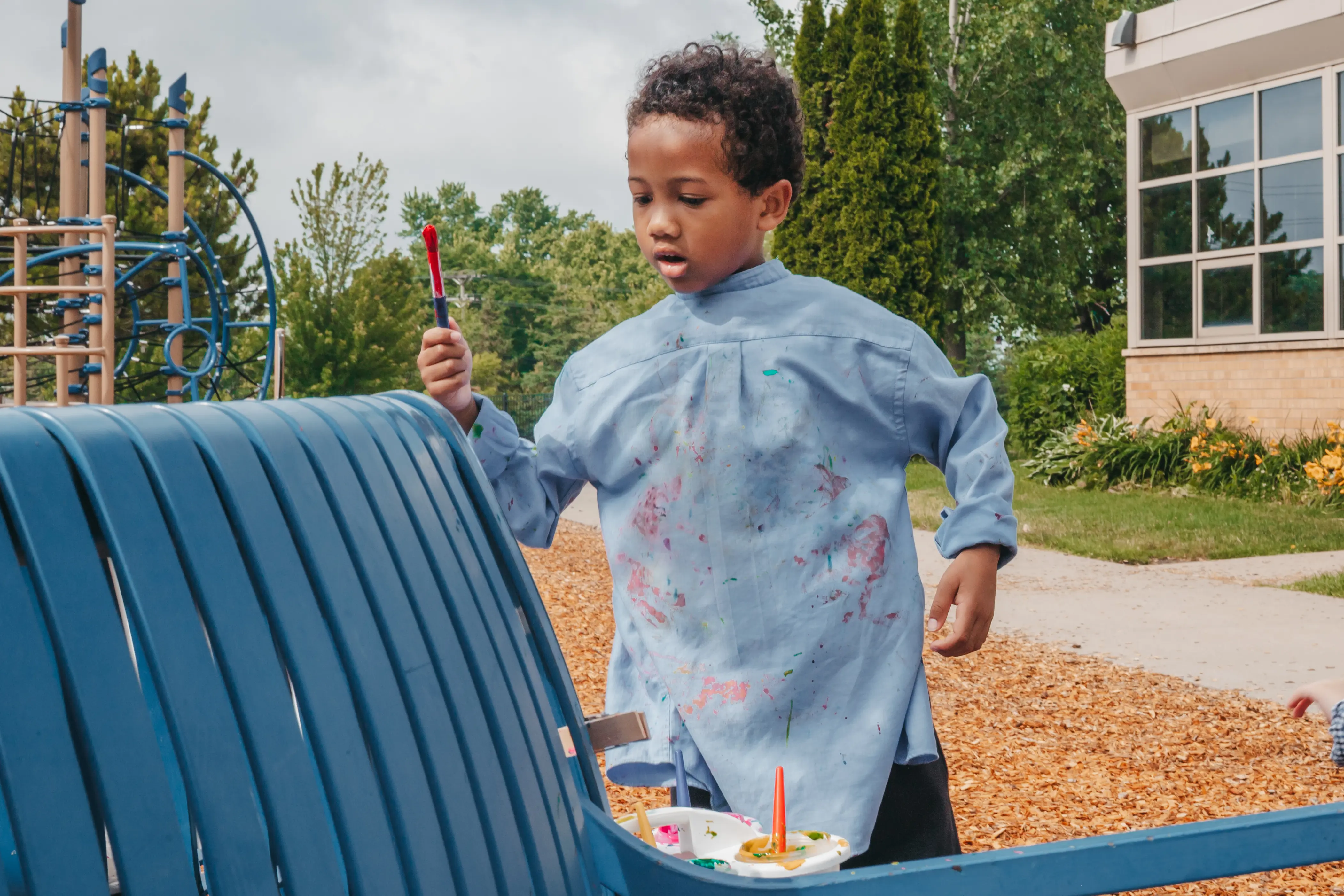 Lower school student creating paint art outdoors
