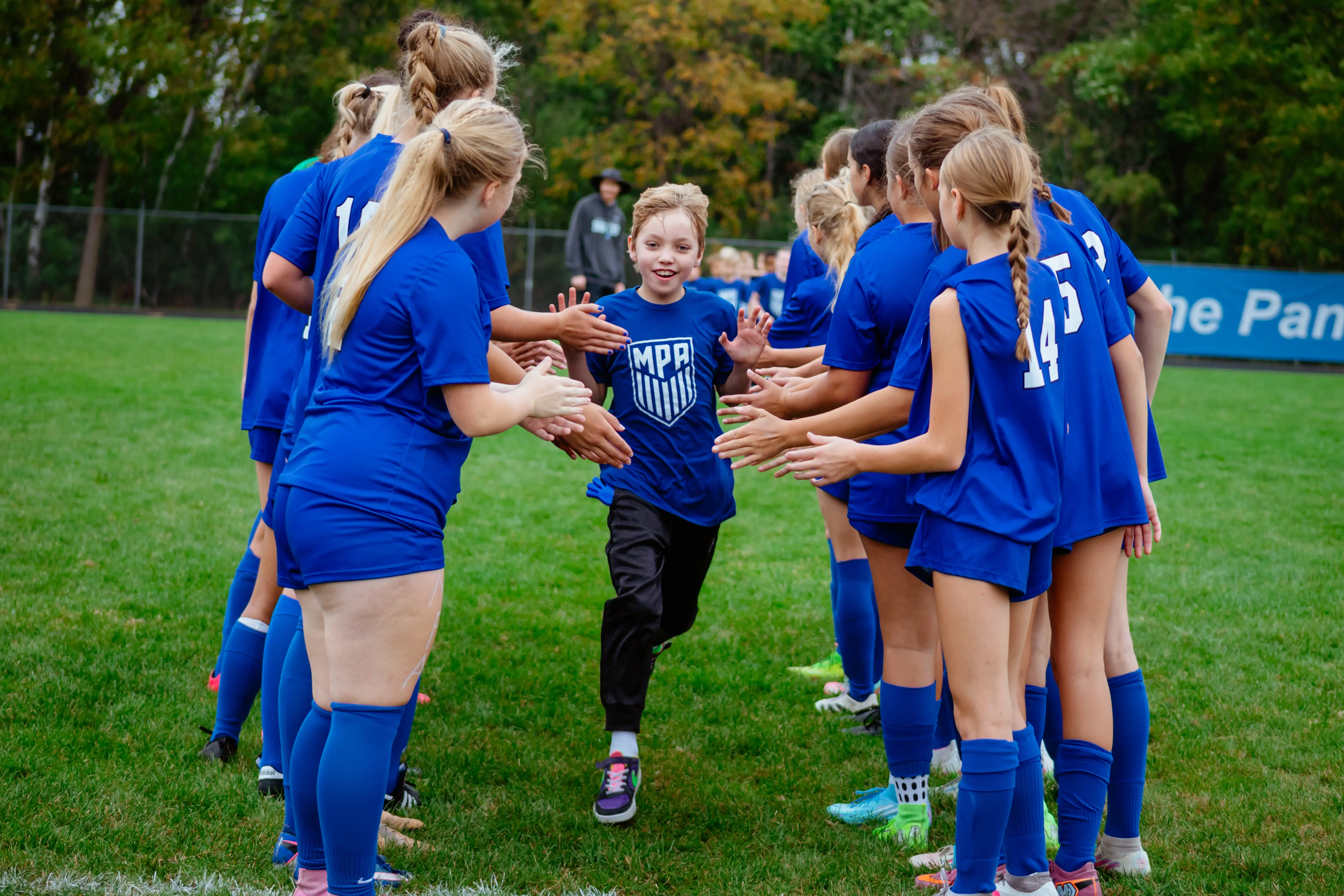 Lower School student is high fived by the girls soccer team