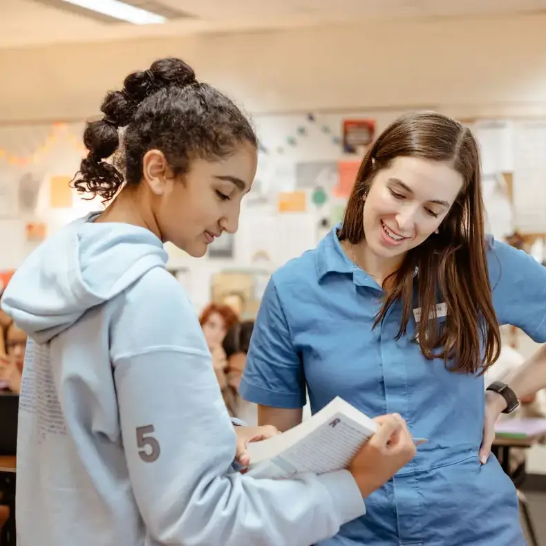 teacher and students looking at a text book