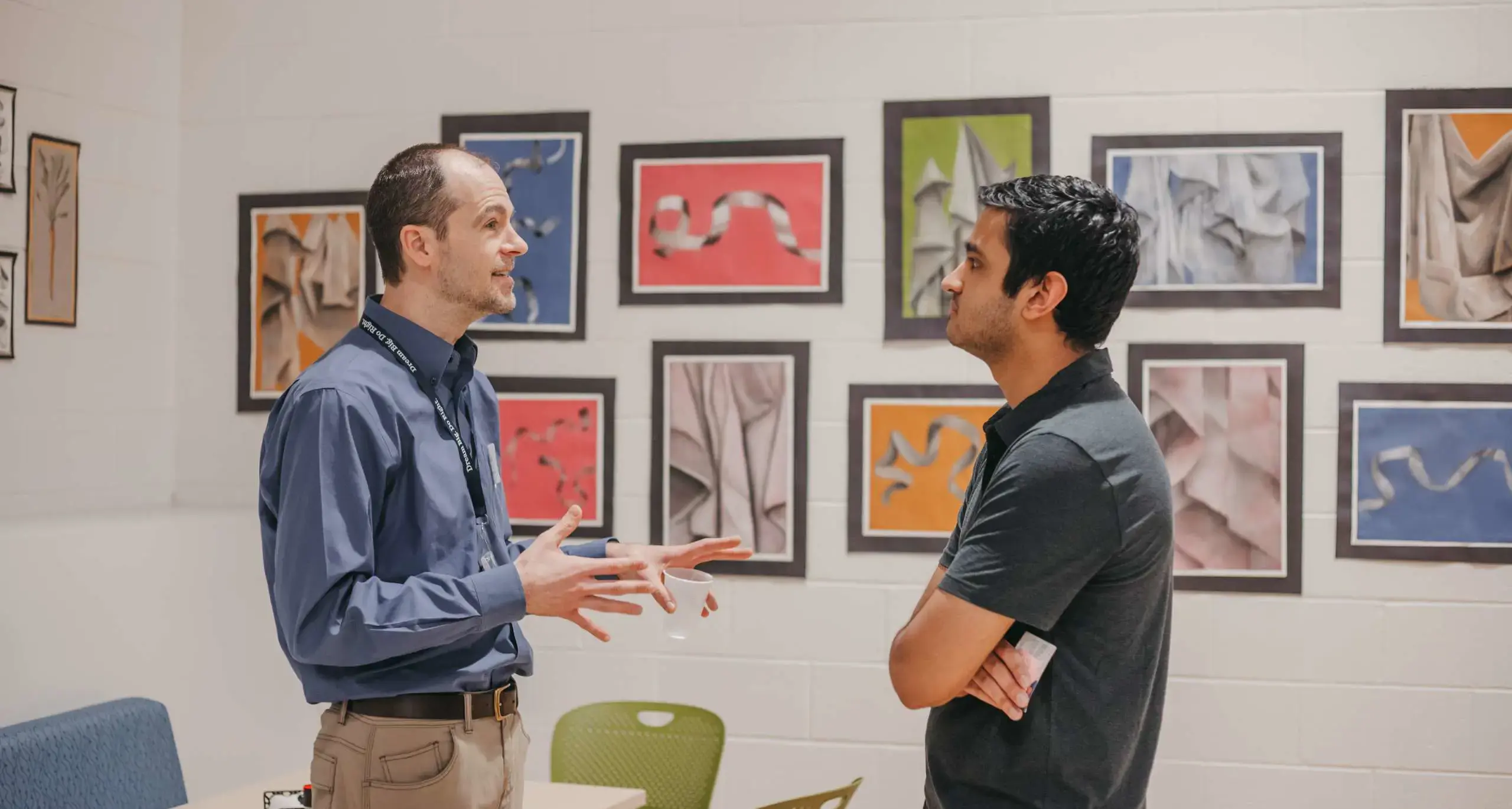 Alumni and staff member talking in the school art gallery.