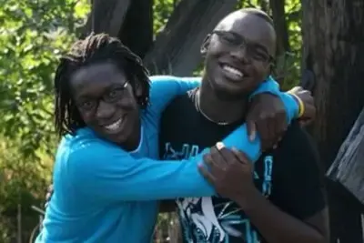 Two alumni students  hugging and smiling at the camera
