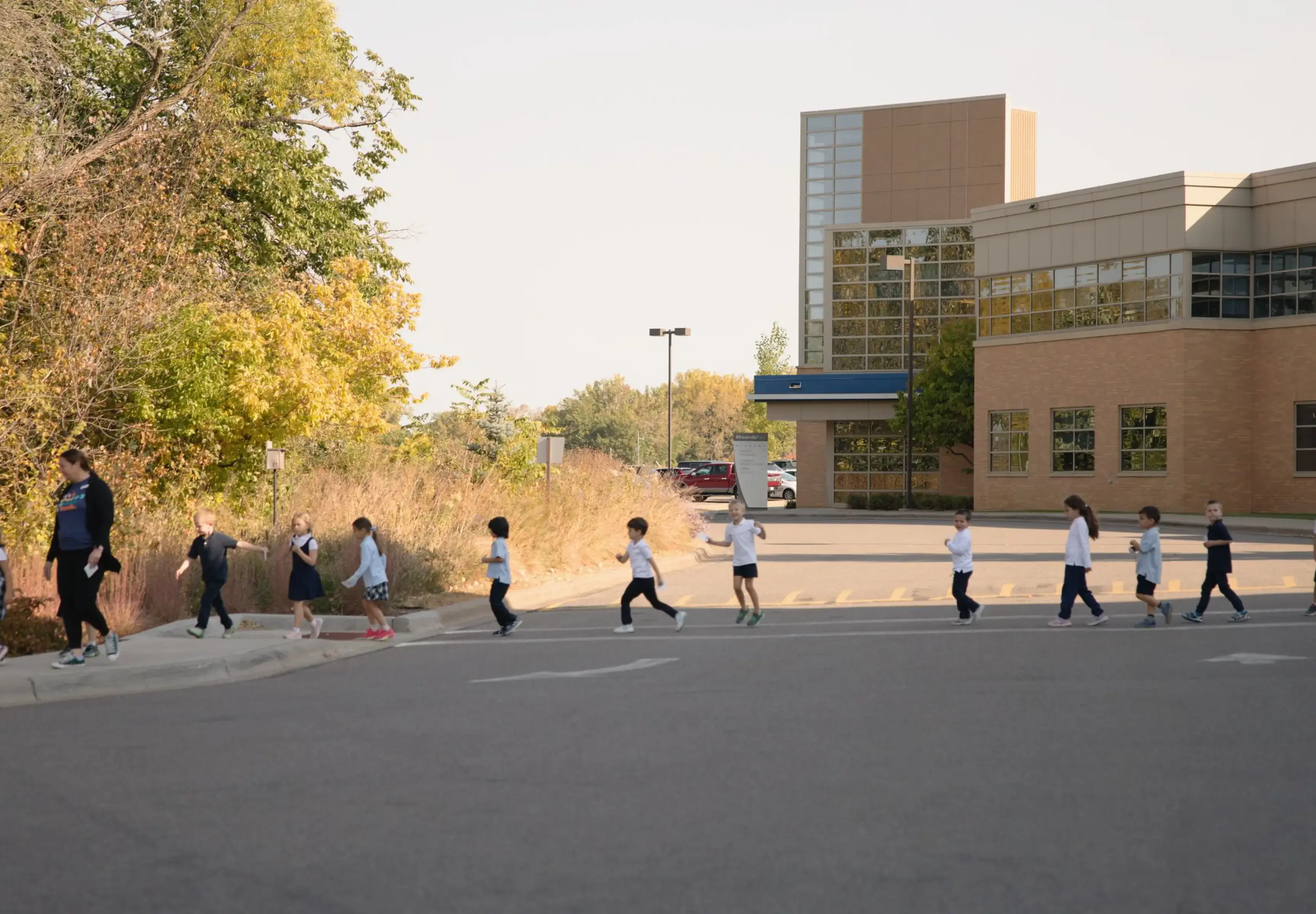 Students crossing the road guided by a teacher