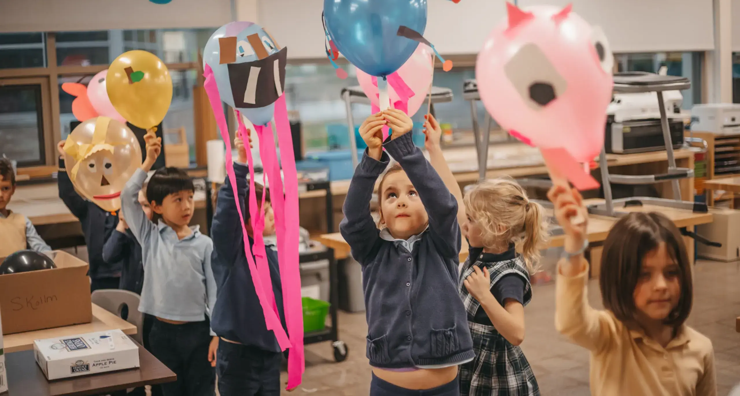 Lower school students playing with decorated balloons in a classroom