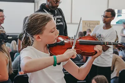 Middle school student playing a string instrument. 