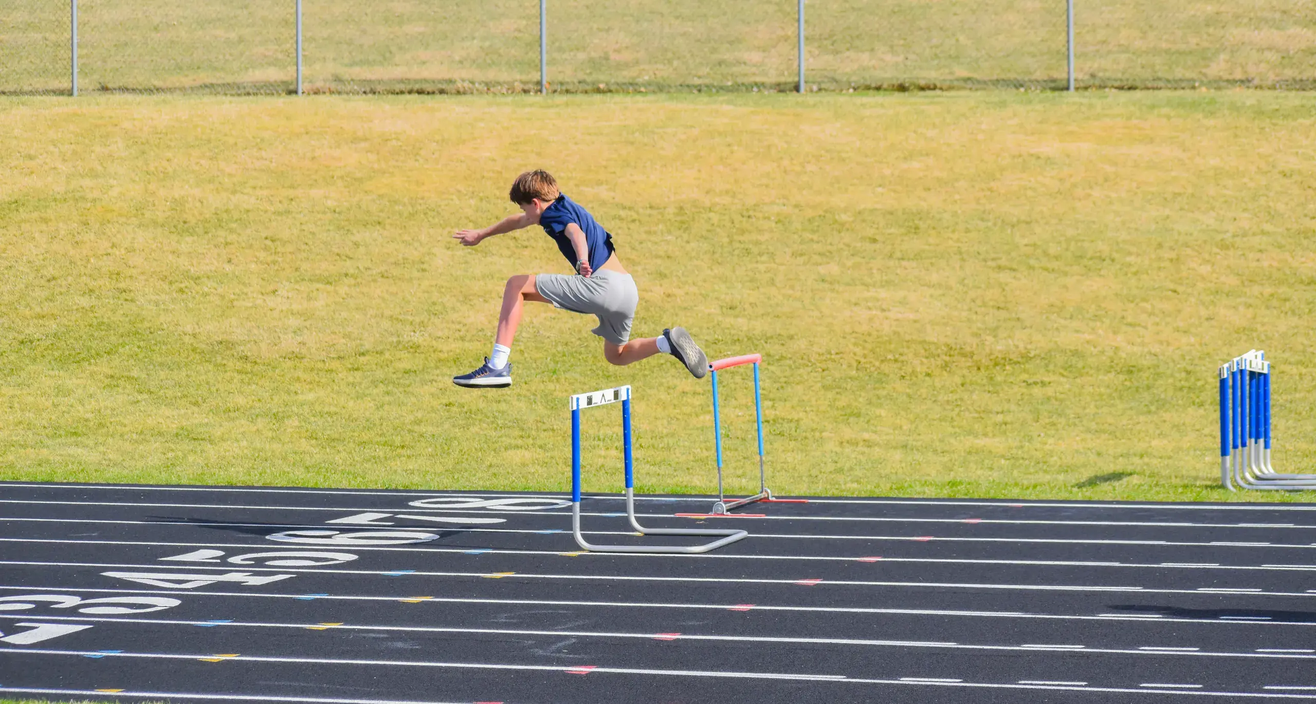 Student jumping hurdles during track practice