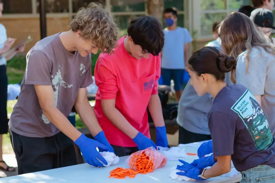 Students wearing gloves work together on a hands-on outdoor service project.