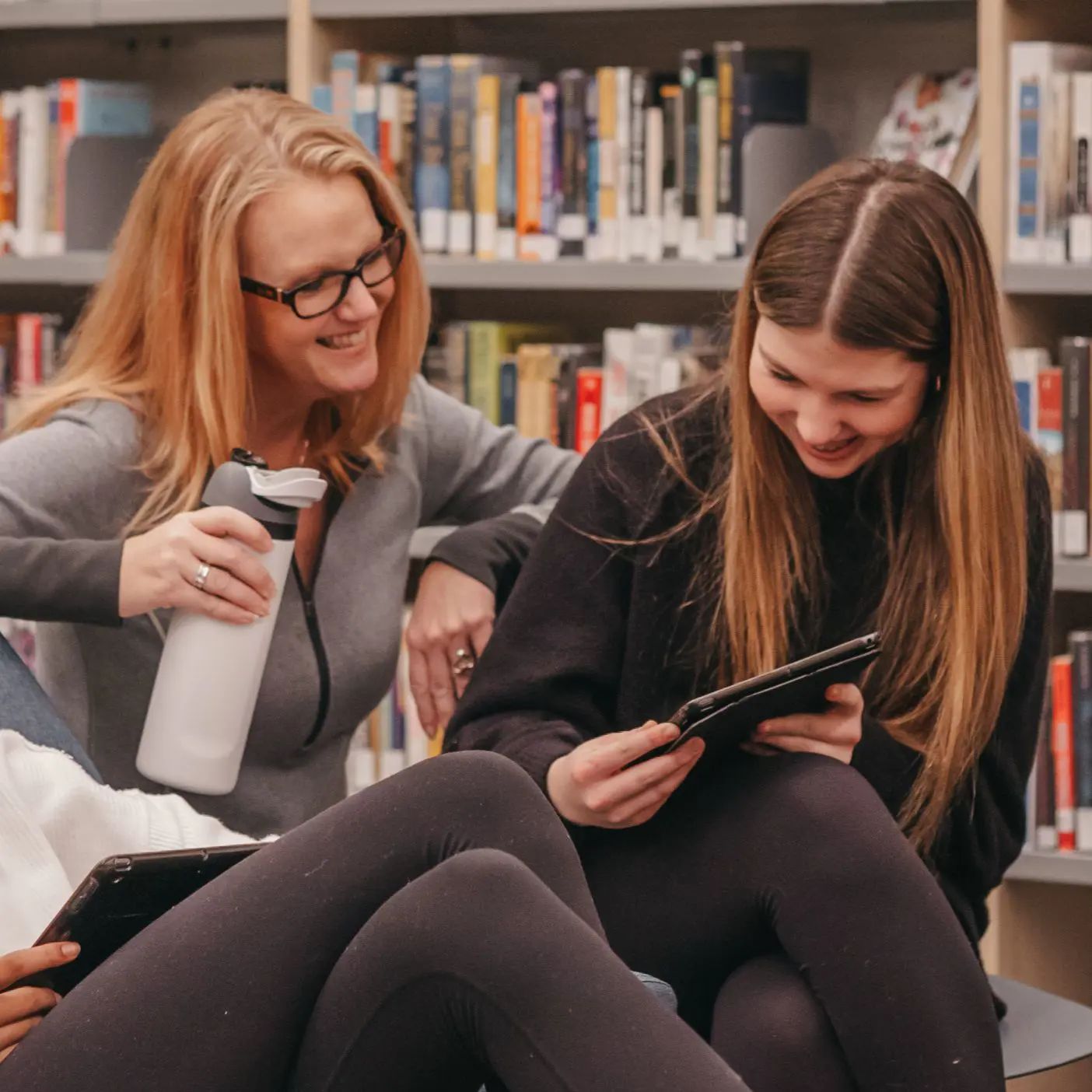 Teacher and student using a tablet in the library.