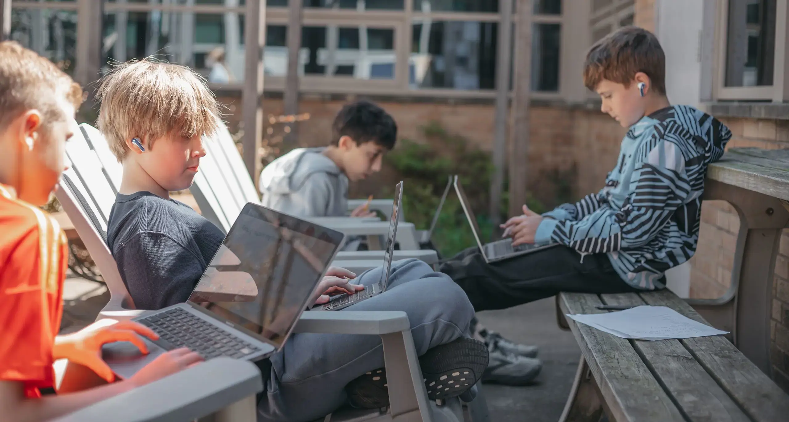 Middle school students sitting outdoors with their laptop