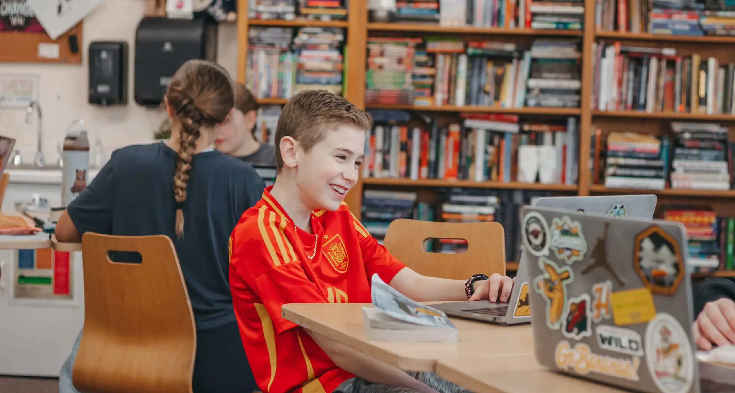 Middle school student using a laptop in the library.