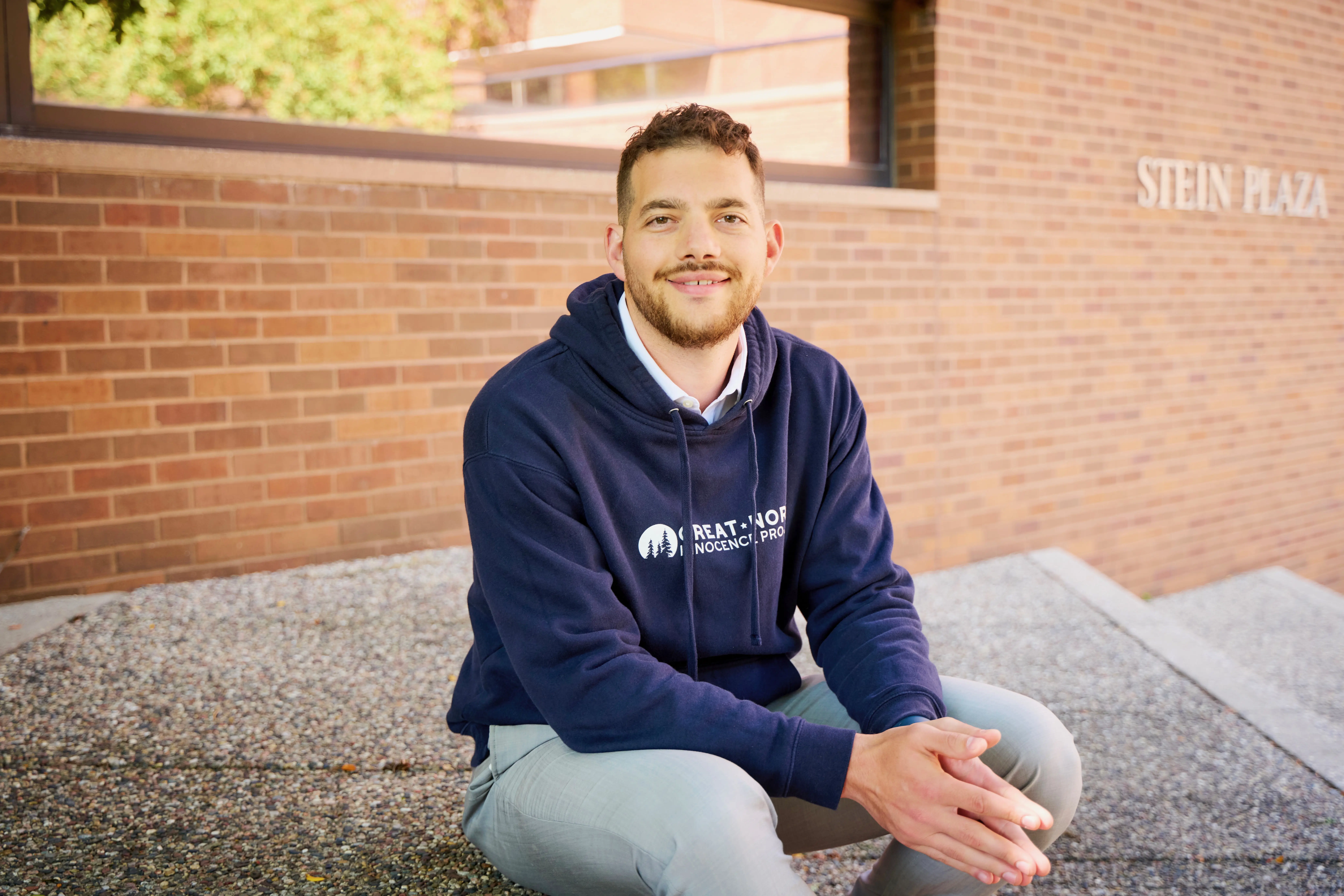 Nate bander sitting on a step outside of a law school.