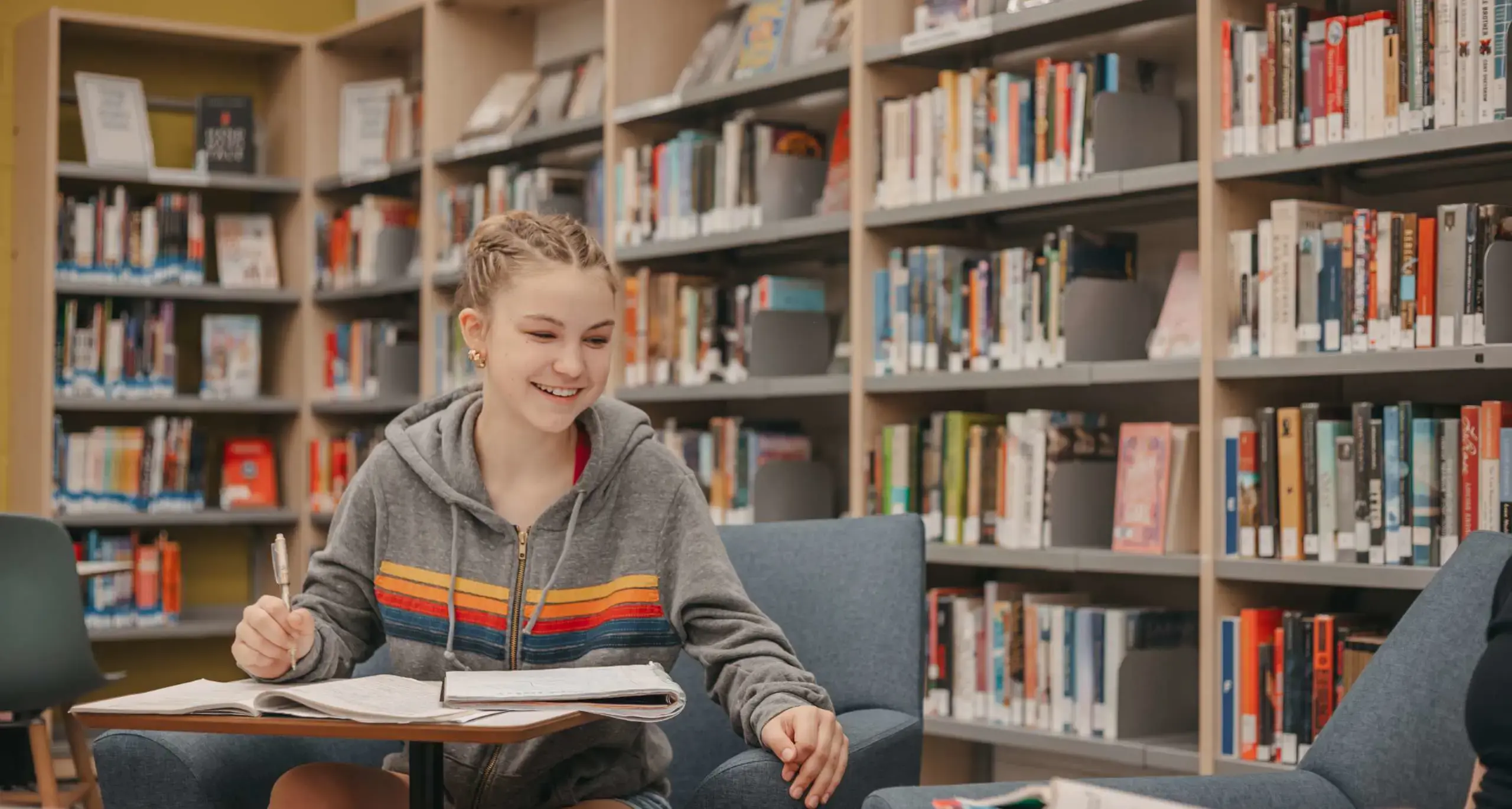 Student studying in the library with books and notebook.