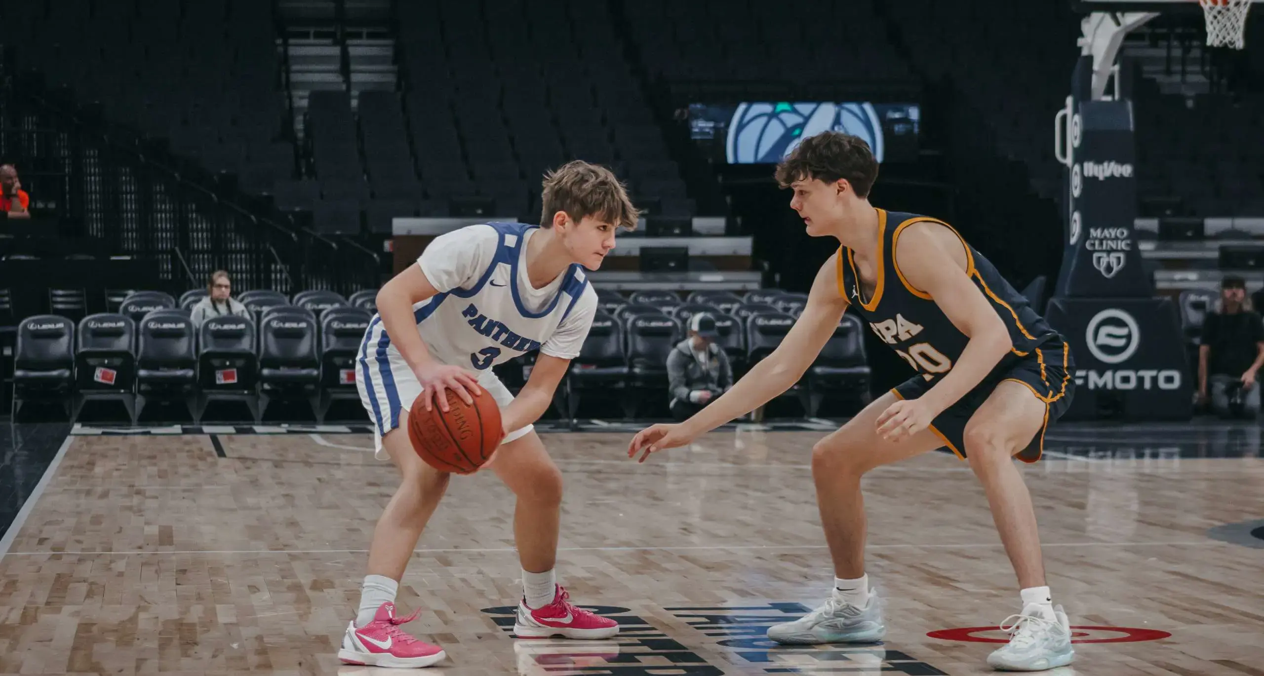 Two high school basketball players competing on the court.