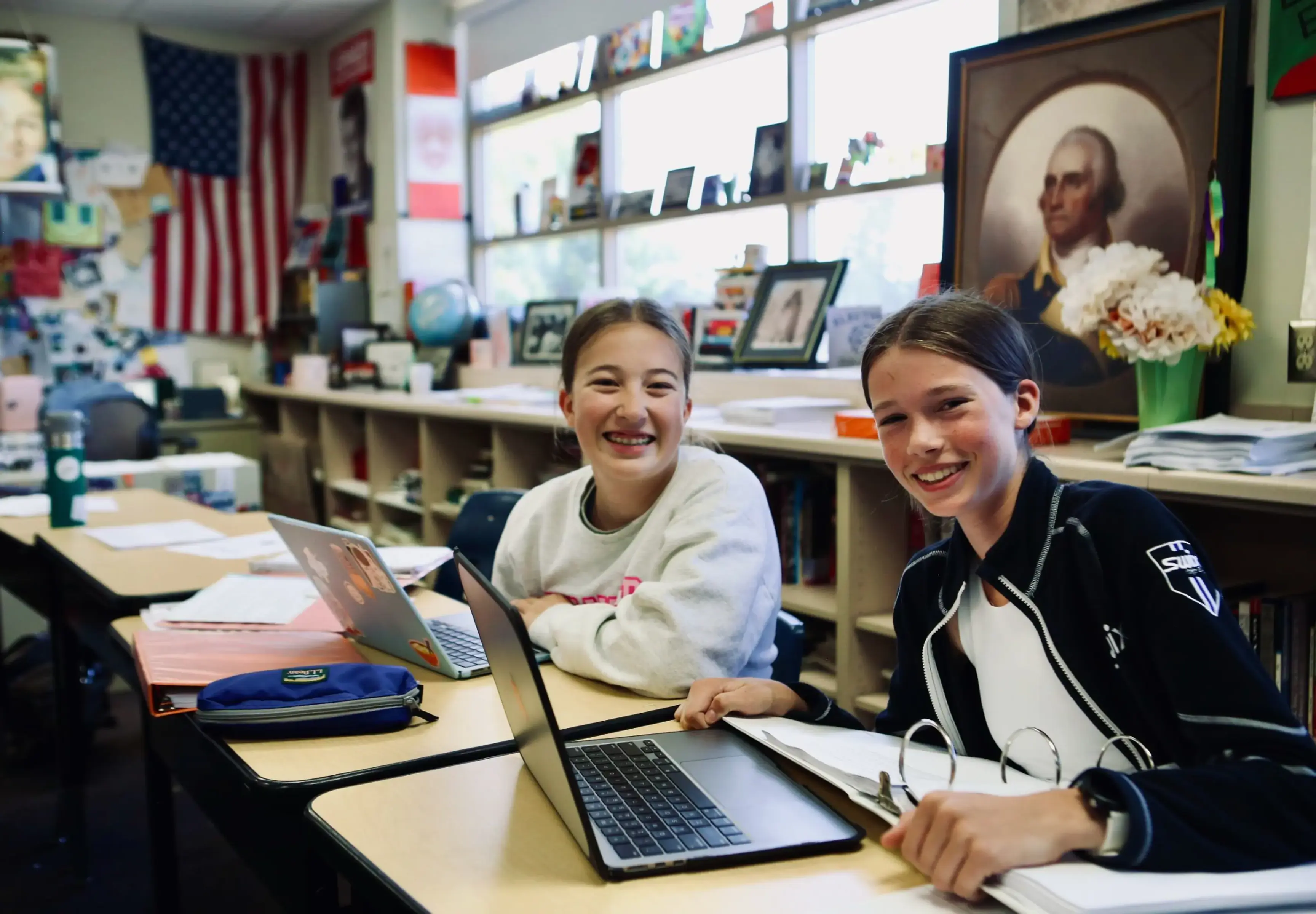 Students collaborating with laptops in a history classroom.