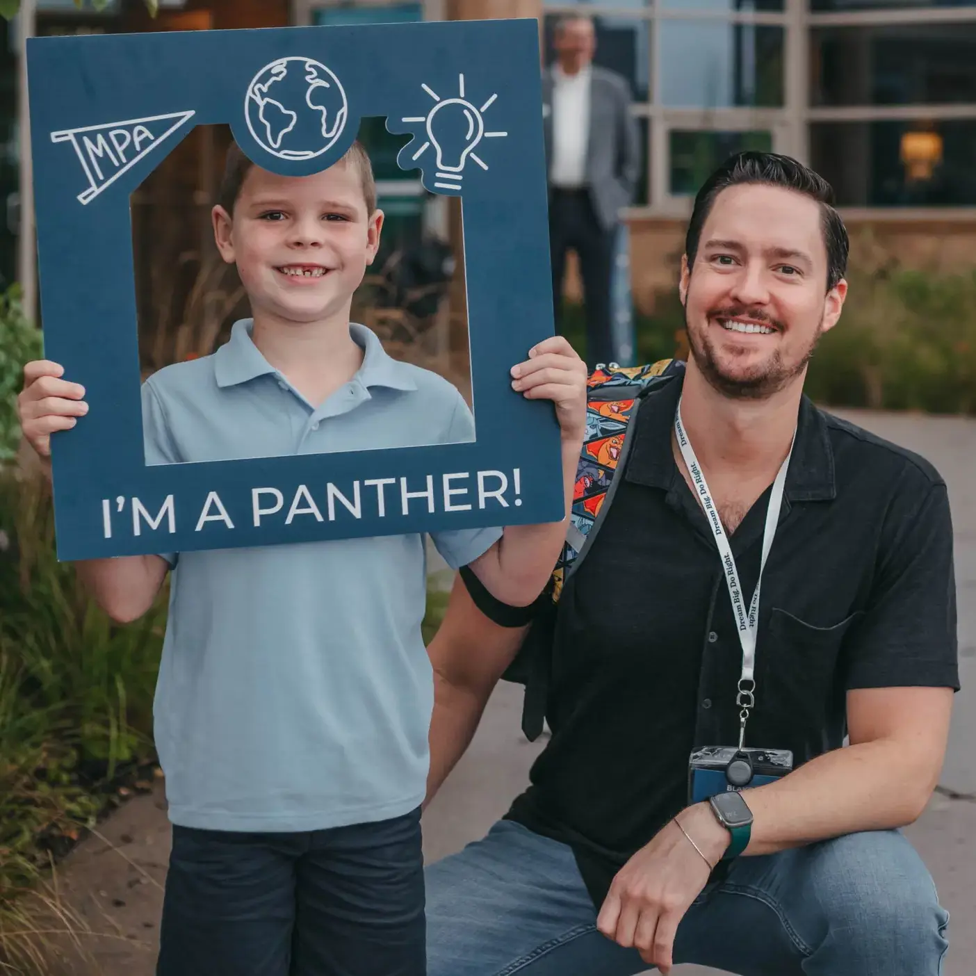 Student and teacher holding an “I’m a Panther!” sign outdoors.