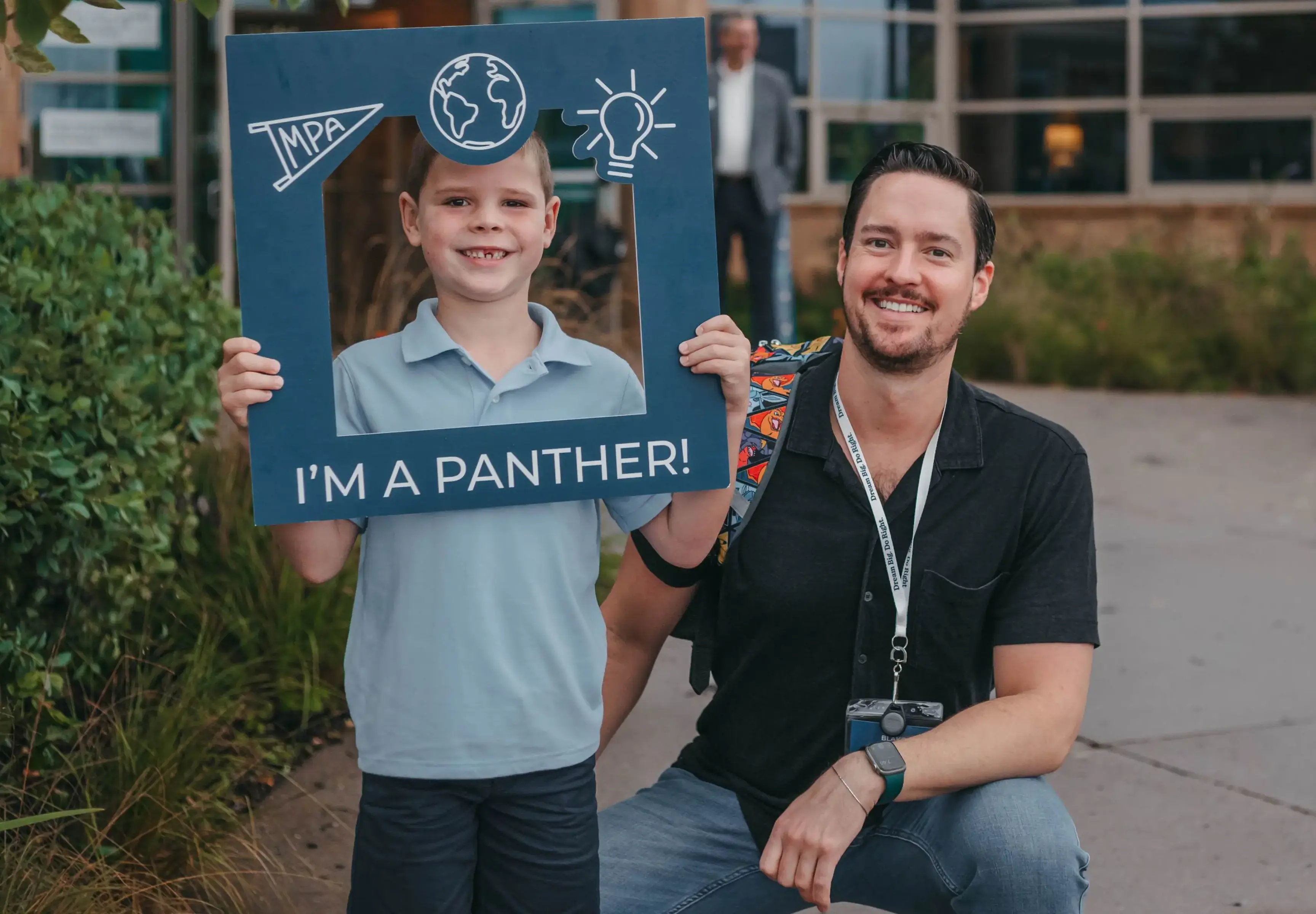 Student and teacher posing with a school spirit sign