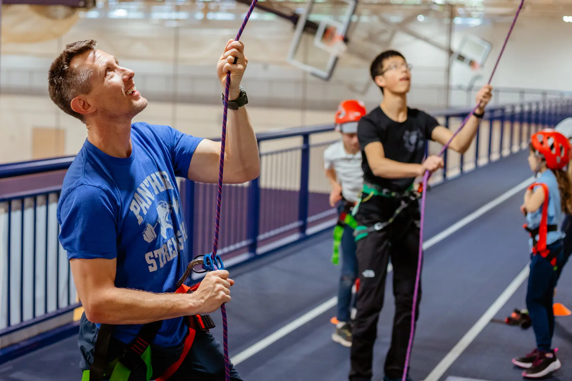 Teacher supervising students during an indoor rock climbing activity.