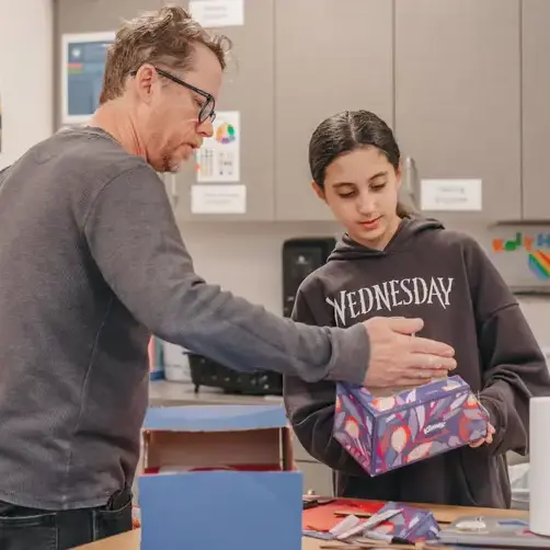 Teacher supporting a student during a hands-on classroom activity