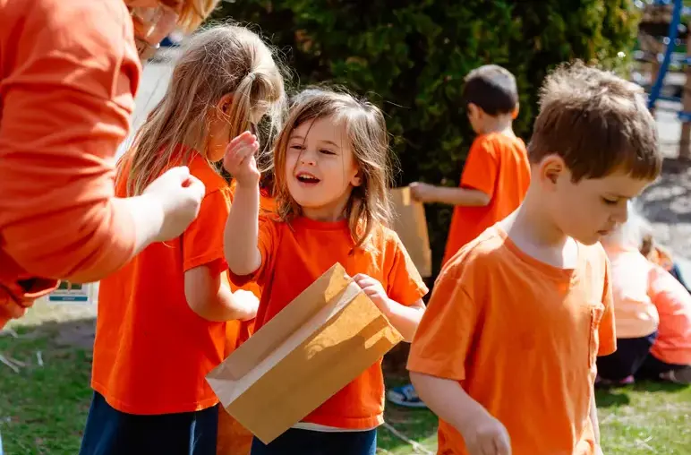 Lower school student showing a flower to her teacher
