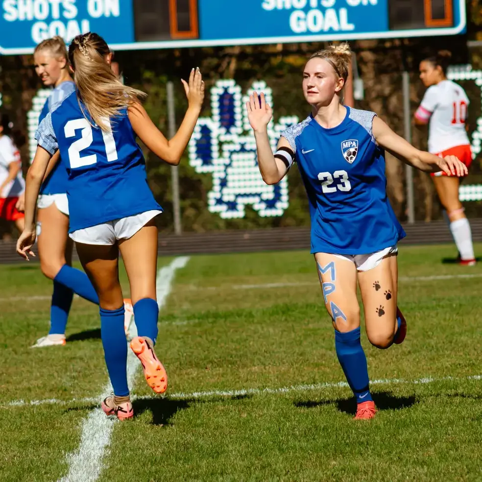 Students celebrating a goal during a football match.