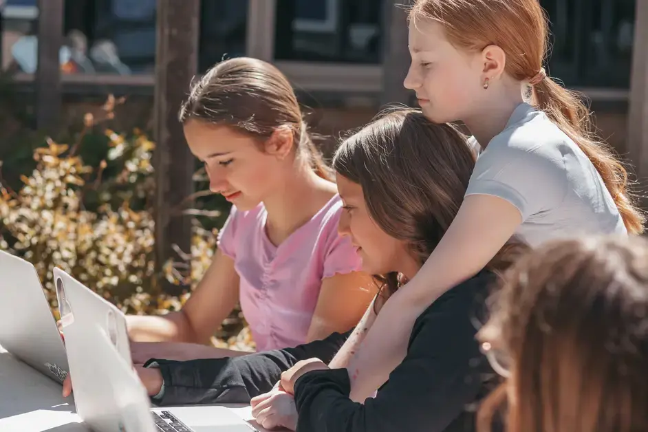 Students using at laptops during a lesson outdoors