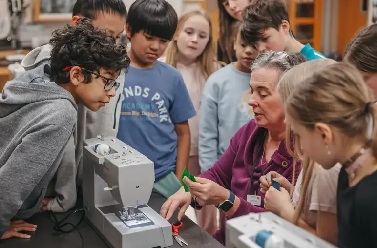 Teacher guiding students through a hands-on sewing machine activity
