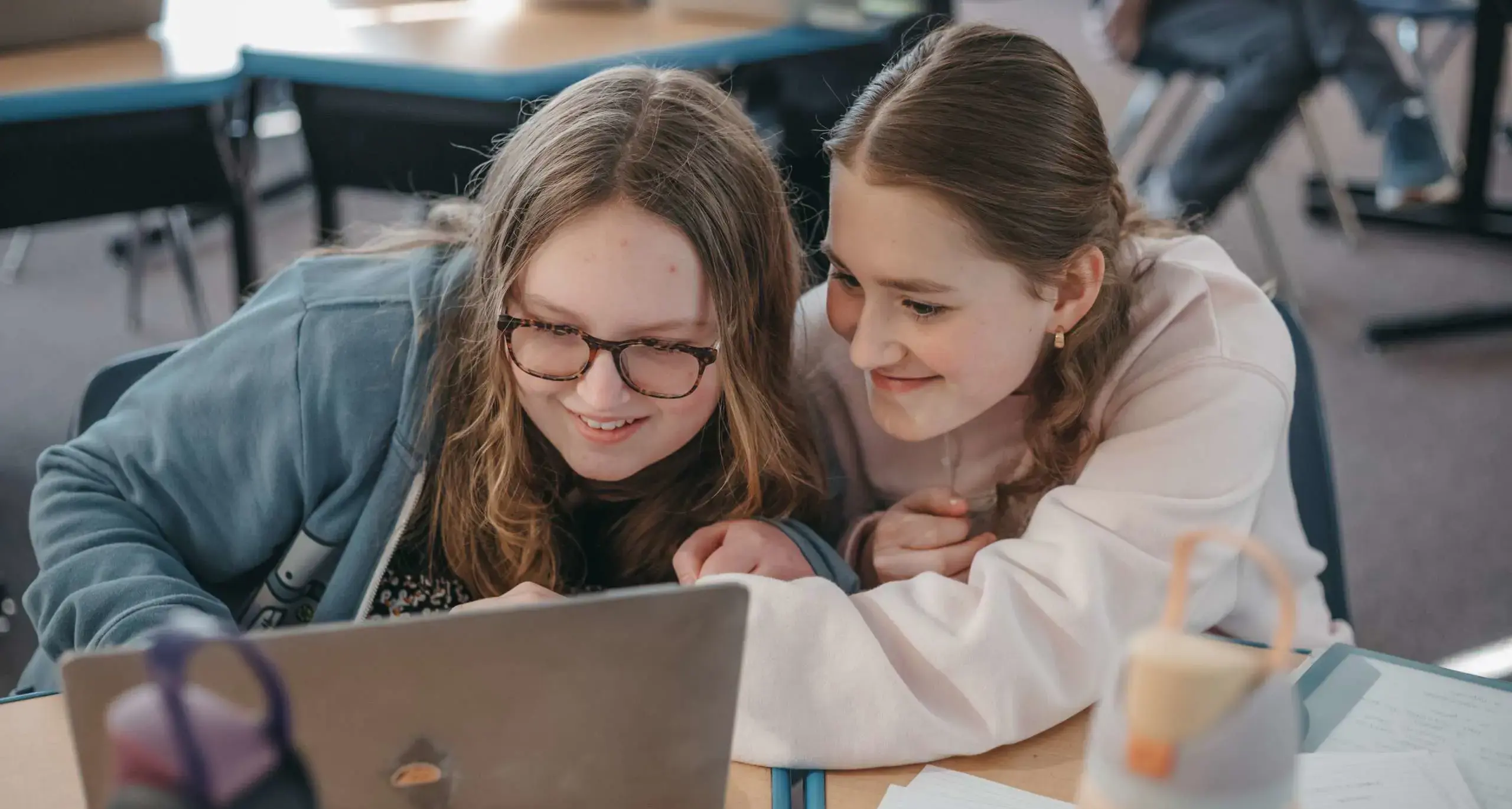 Two students collaborating on a laptop in class.